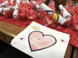 a table adorned with valentines-day themed goody bags with artwork depicting why students love their community school